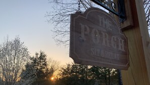 A wooden sign with the text "The Porch Sit & Relax" against a backdrop of trees and a sunset. - Skip the Steep Roads! Family Cabin Hot Tub Near PF (Sevierville)