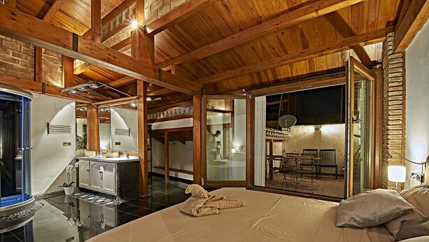 A spacious bedroom with a large bed, a wooden ceiling, and a view of the outdoor patio area. - My Special Place - An exceptional Loft (Málaga)