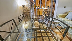A dining area with a glass table, chairs, and a stone wall. - My Special Place - An exceptional Loft (Málaga)