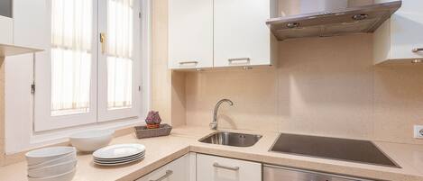 A modern kitchen with white cabinets, a stainless steel sink, and a built-in oven.