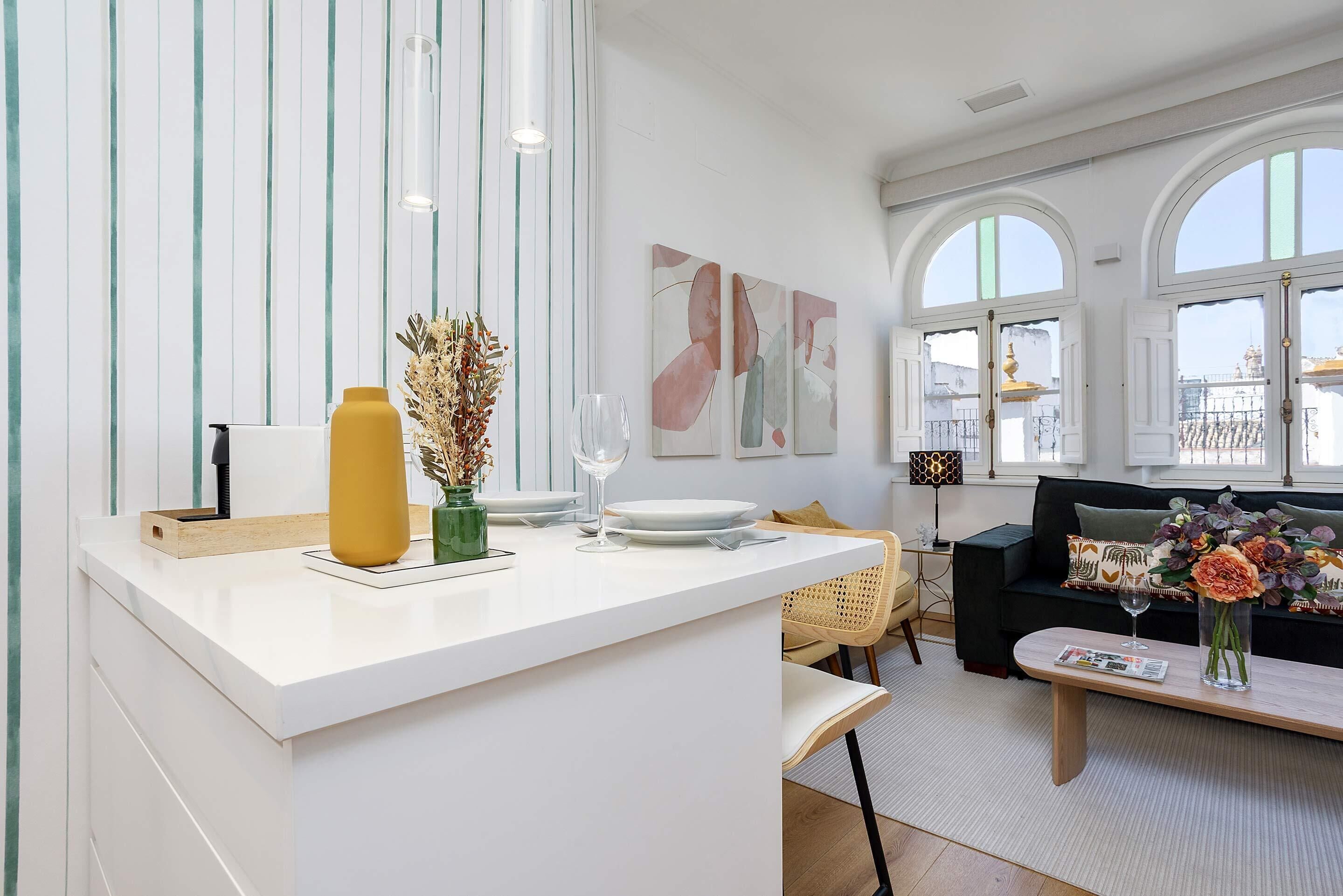 A modern living room with a white reception desk, a black sofa, and a large window with a view of the city.