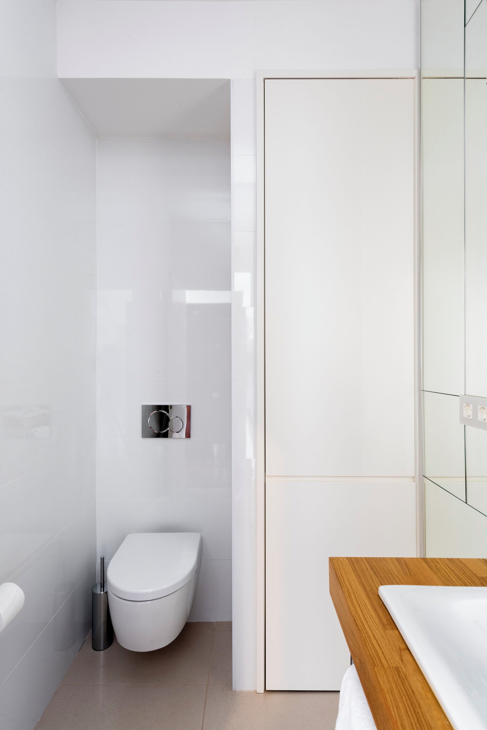 Un baño moderno con inodoro blanco, bidé y tocador de madera.