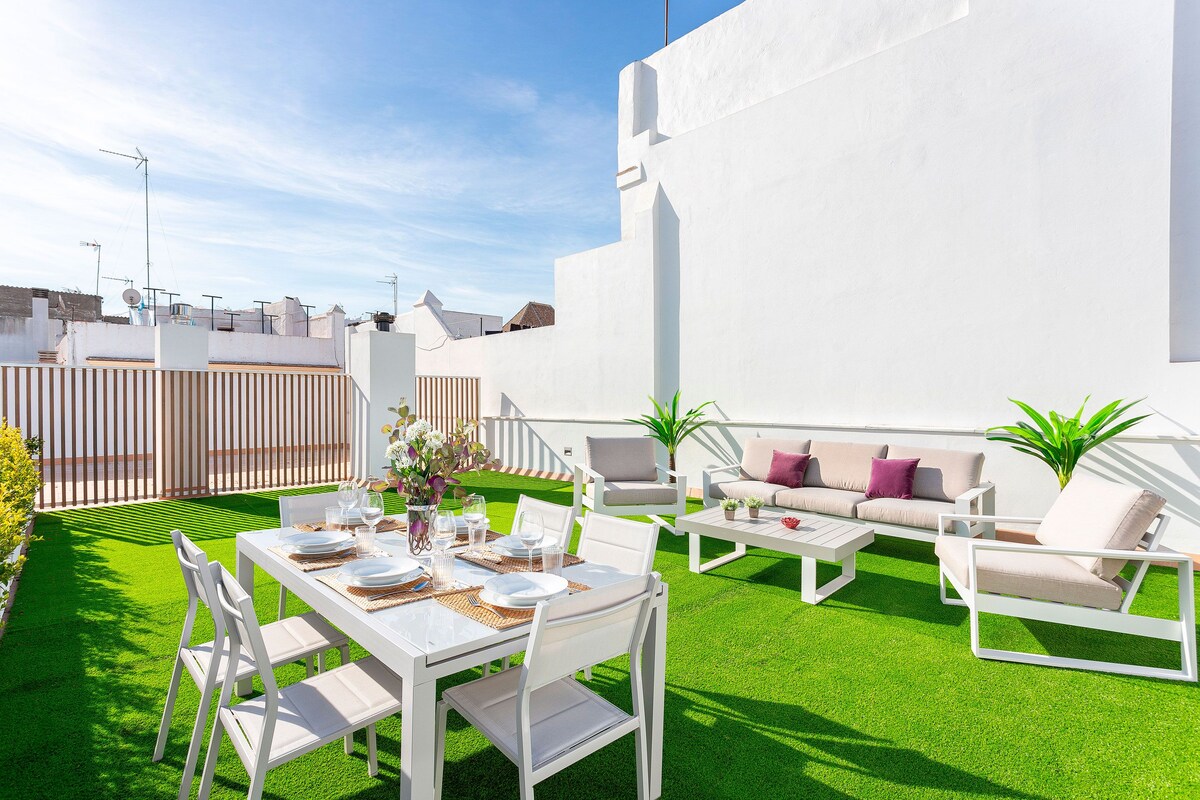 En tagterrasse med et spisebord til fire, udendørs møbler og udsigt over bybilledet.