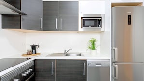 A modern kitchen with dark wood cabinets, a stainless steel refrigerator, a built-in microwave, and a dishwasher. - Genteel Home Marin Garcia IV (Málaga)