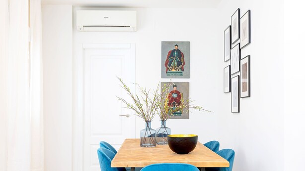 A dining area with a wooden table, blue chairs, and a vase with branches. - Genteel Home Marin Garcia IV (Málaga)