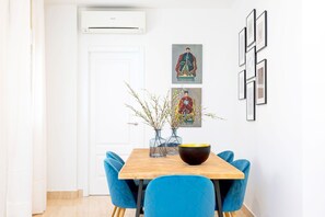 Uma sala de jantar com uma mesa de madeira, cadeiras azuis e um vaso com galhos.