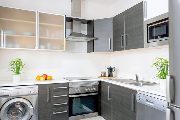 A modern kitchen with a washing machine, oven, microwave, and dishwasher.