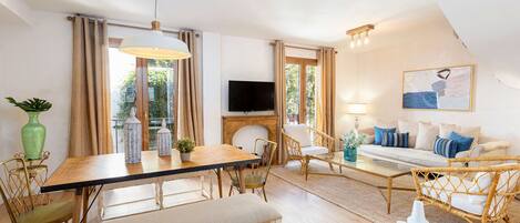 A well-lit living area with a dining table, chairs, a sofa, and a television.