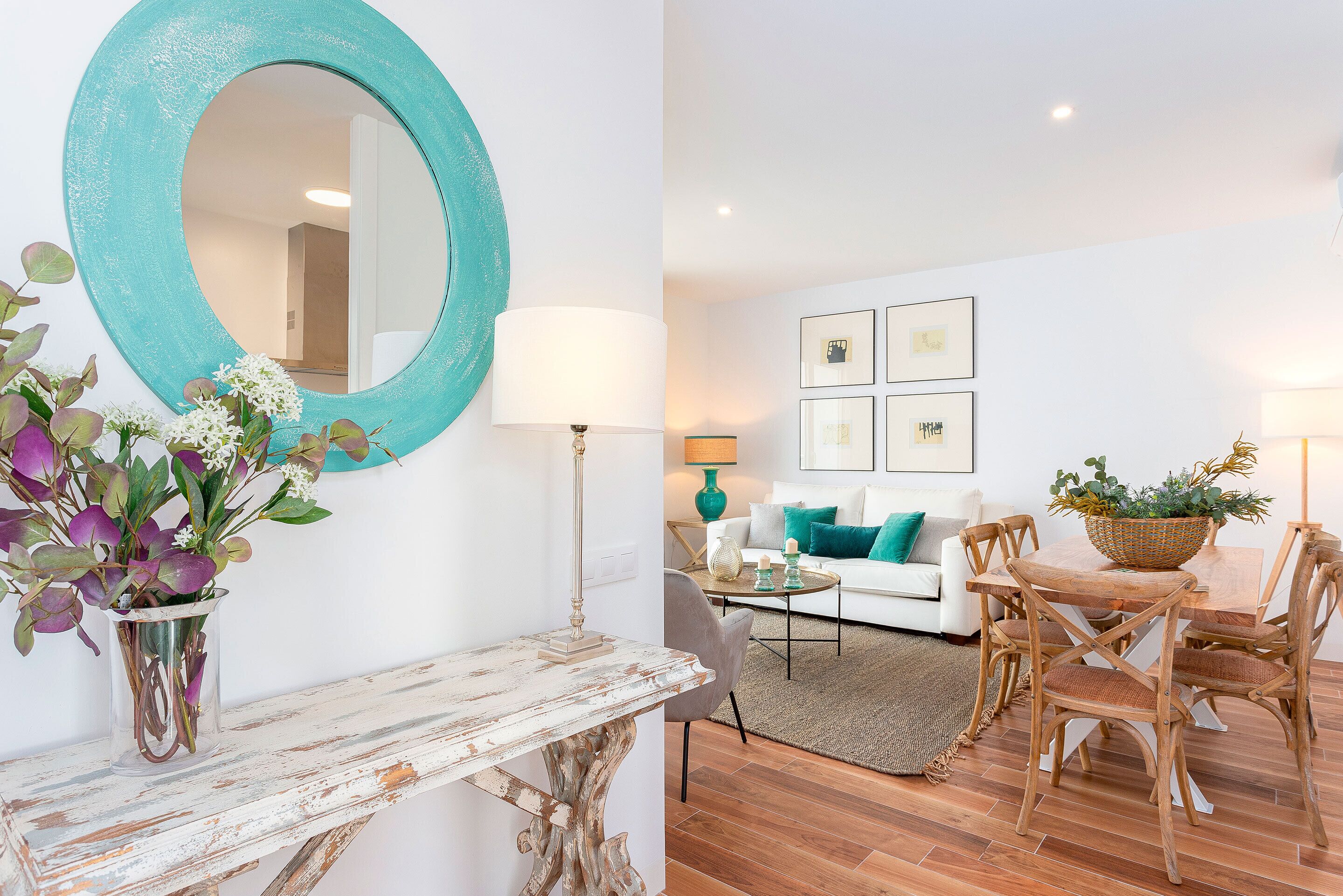 A living room with a white sofa, a coffee table, and a dining area with wooden chairs and a table.