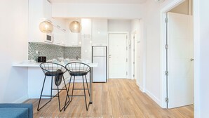 A modern kitchen with white cabinets, a microwave, and a dining area with two black chairs. - 1 Bd Apartment With Balcony Perfect Location. Santa Marta II (Seville)