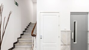 A staircase with a wooden handrail, a white door, and a grey door with a small window. - Genteel Home Marin Garcia I (Málaga)