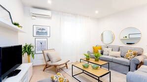A modern living room with a flat-screen TV, a grey sofa, a coffee table, and a chair. - Genteel Home Marin Garcia I (Málaga)
