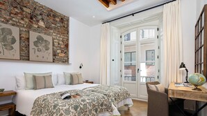 A bedroom with two beds, a desk with a globe, and a brick wall with botanical prints. - Genteel Home Plaza de la Marina (Málaga)
