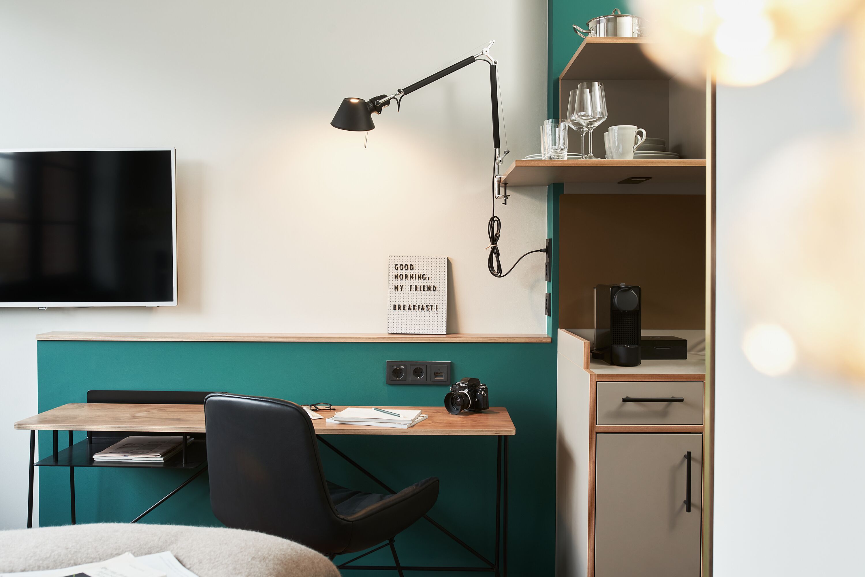 Una habitación moderna con escritorio, silla y televisor montado en la pared.
