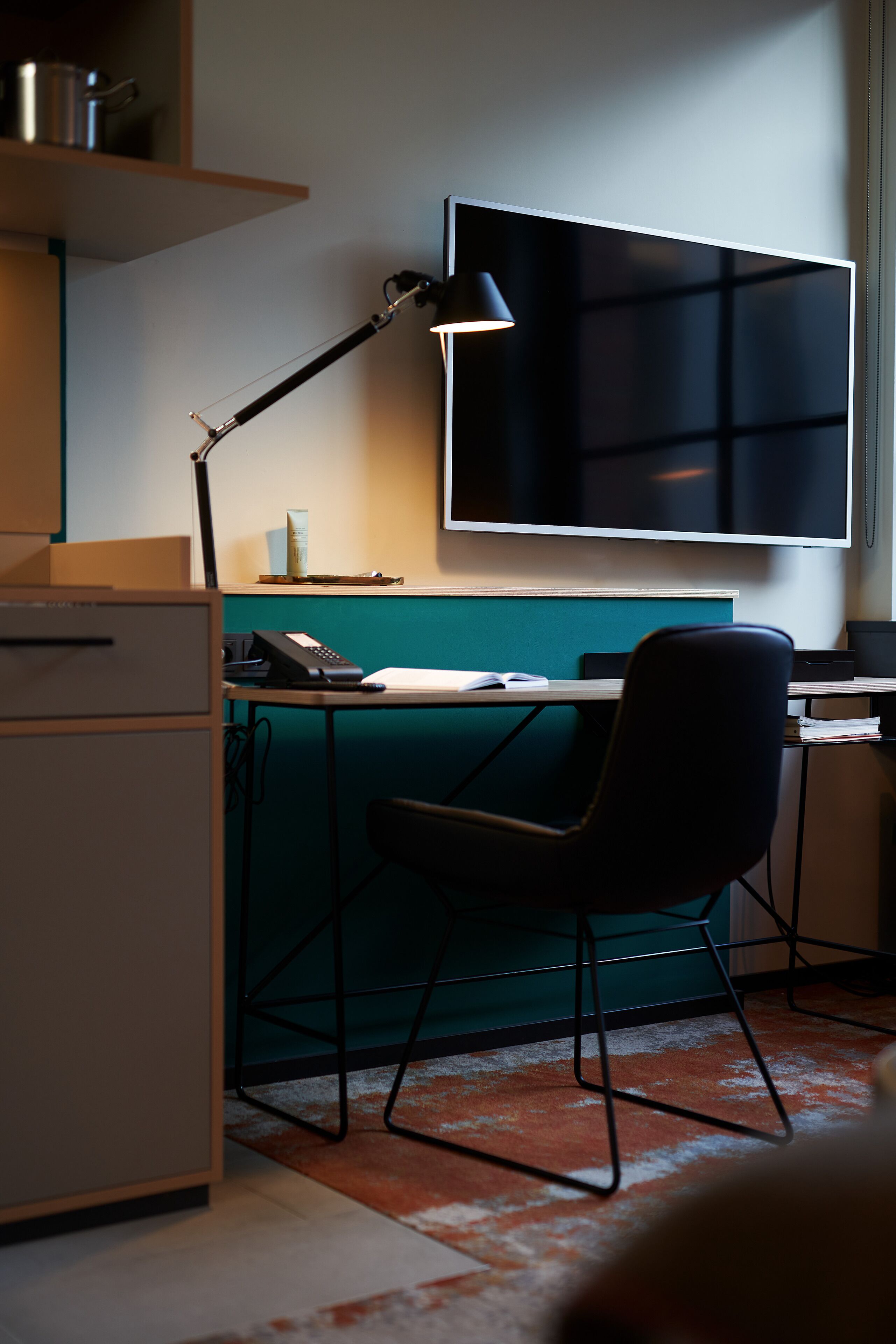 Un espai d'oficina modern amb escriptori, cadira i un monitor gran.