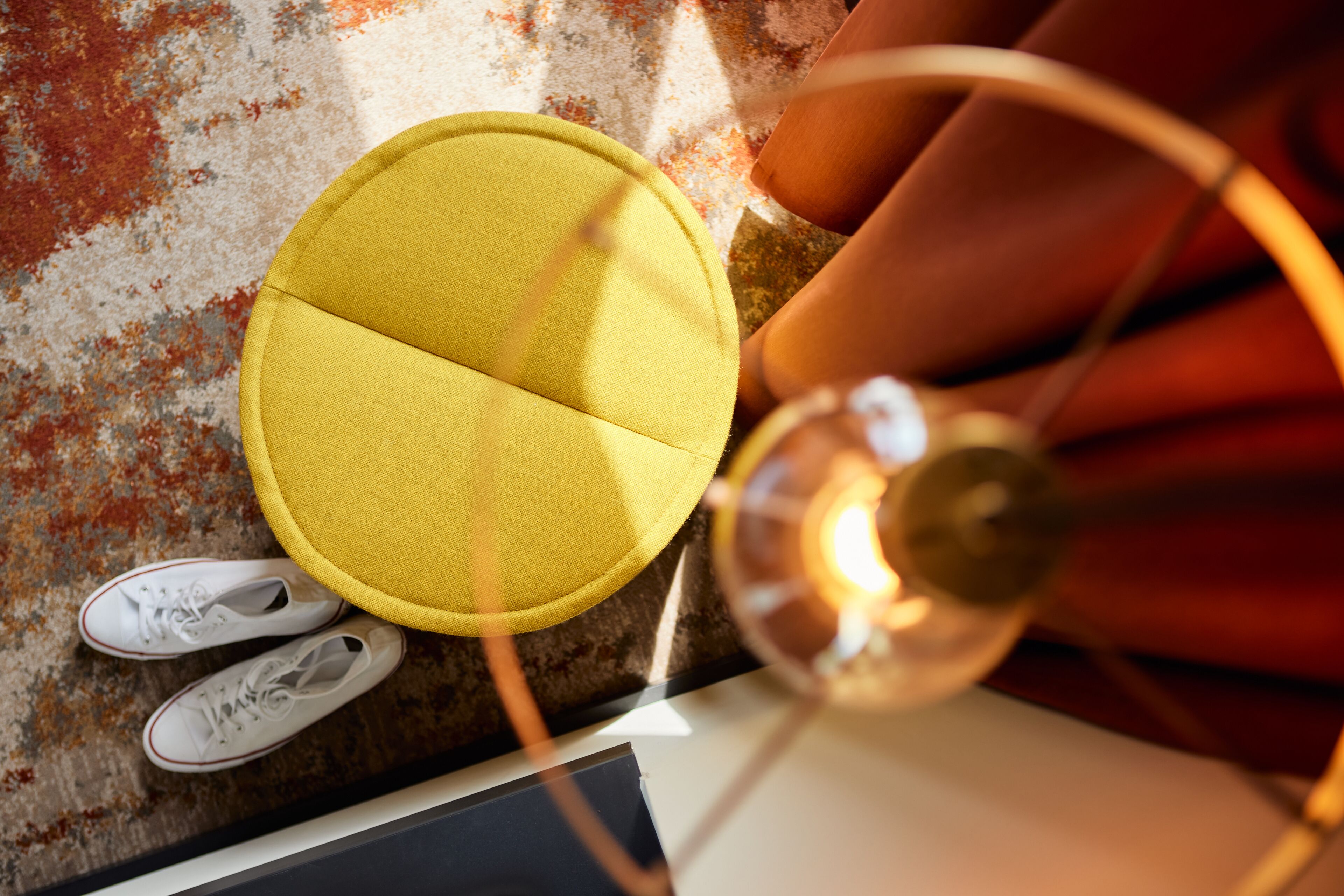 A top-down view of a room with a yellow circular object, white shoes, and a light fixture.
