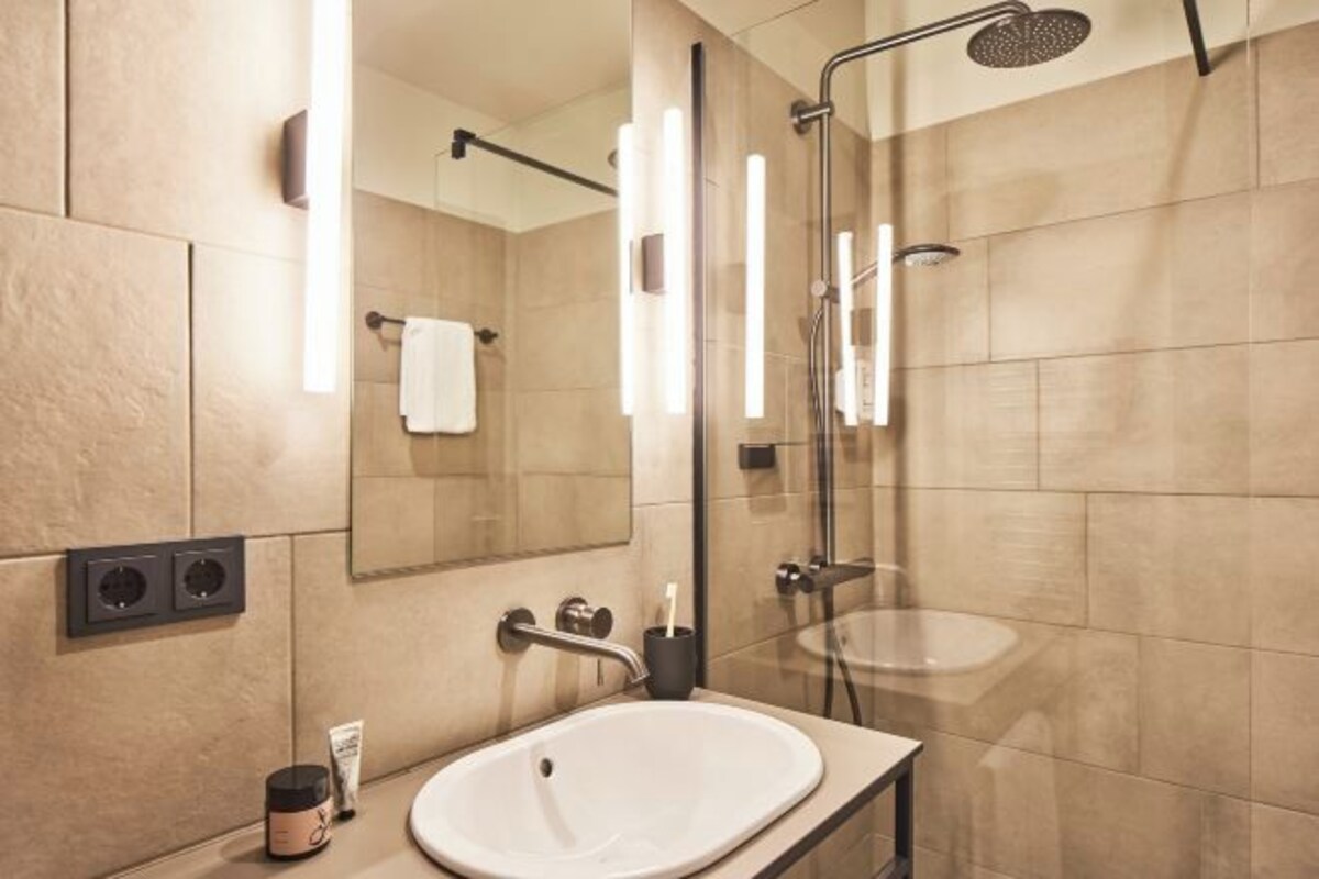 A modern bathroom with a large mirror, a sink, and a glass-enclosed shower.