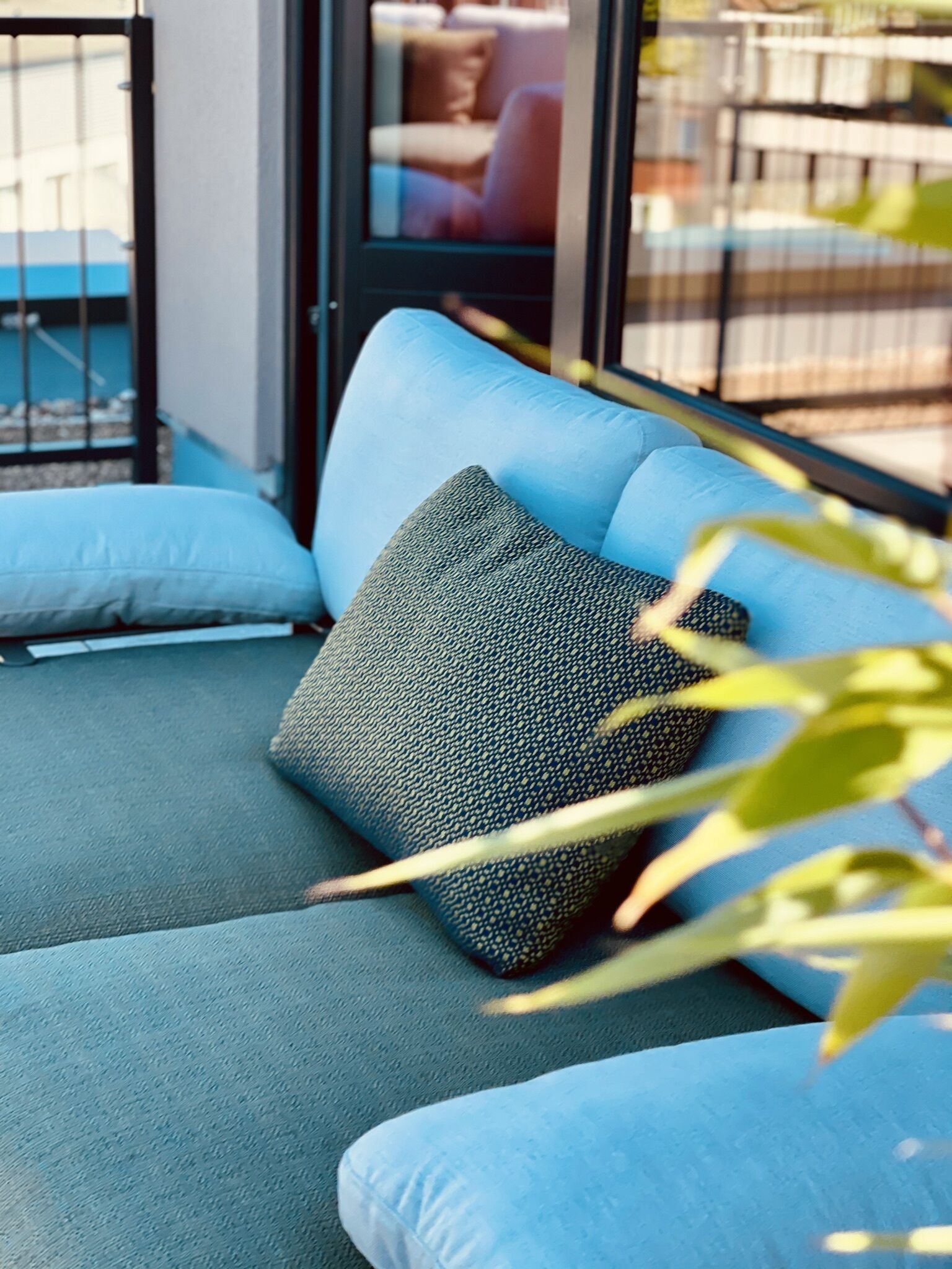 A light blue sofa with a textured pillow and a glass door in the background.
