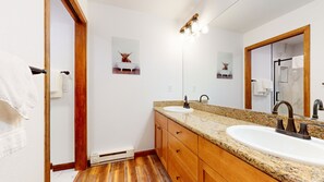 Bathroom features a double sink, wooden cabinetry, and a light fixture.