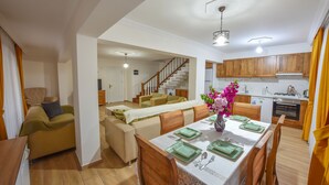 Uma sala de estar moderna com área de jantar, armários de madeira e escada para outro andar.