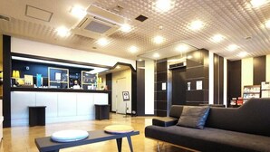 A modern lobby with a reception desk, a sofa, a coffee table, and a wooden floor. - Hotel Areaone Okayama (Okayama)