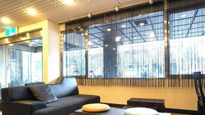 A modern interior with a sofa, ottoman, and a table with a laptop. - Hotel Areaone Okayama (Okayama)