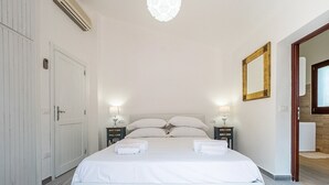 Ein Schlafzimmer mit einem großen Bett, zwei Nachttischen mit Lampen, einem Kleiderschrank und einem Spiegel an der Wand.
