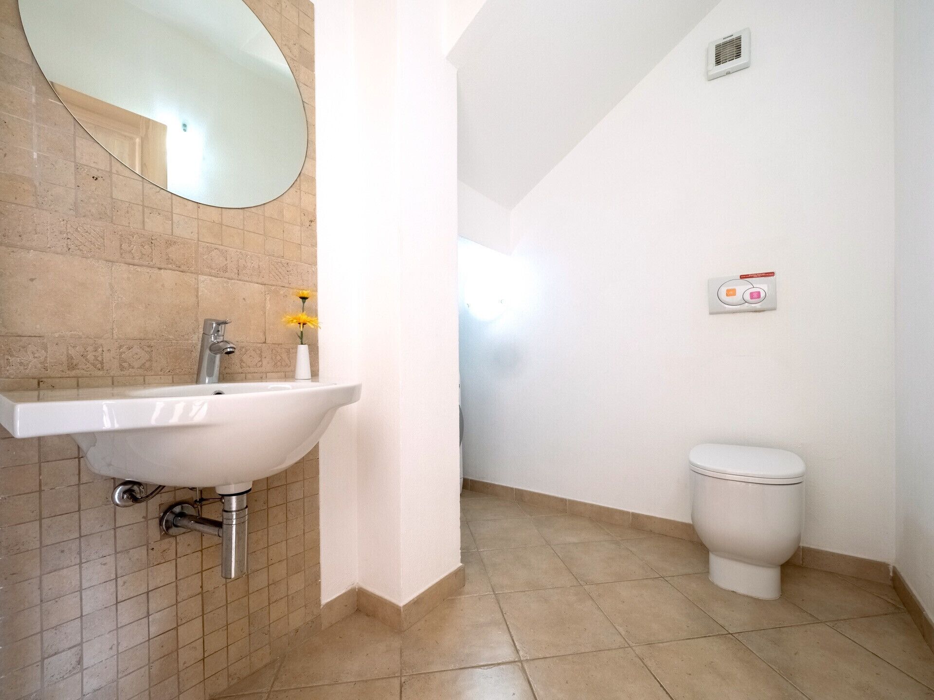 Un baño con un lavamanos blanco, un espejo, un inodoro y un calentador instalado en la pared.
