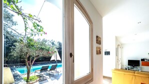 Una habitación con un ventanal que da a una piscina y zona de estar al aire libre.