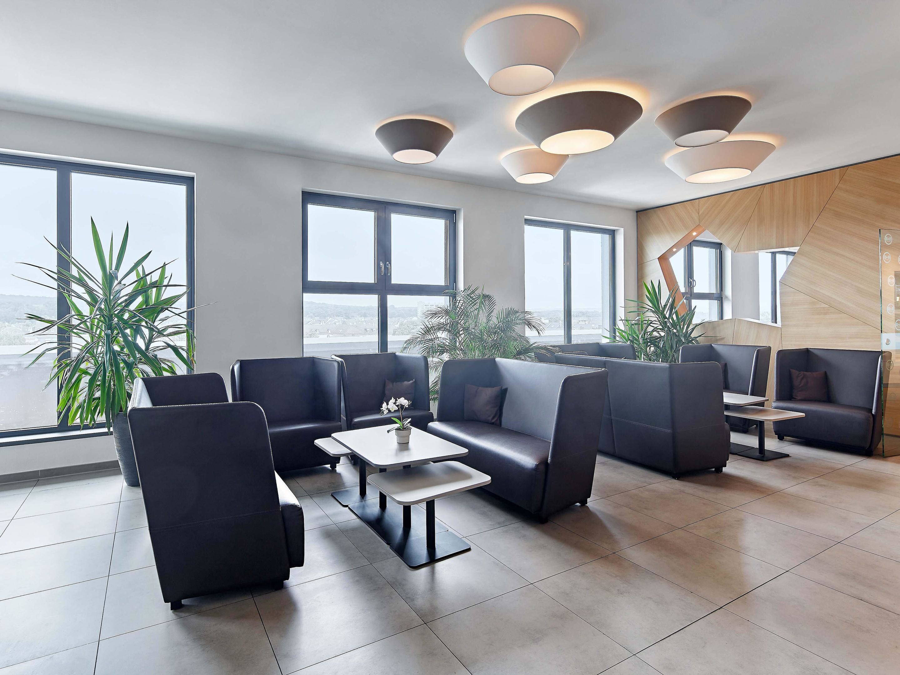 Ein moderner Lounge-Bereich mit Ledersitzgelegenheiten, großen Fenstern und zeitgemäßen Beleuchtungselementen.