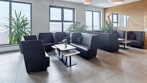 A modern lounge area with leather seating, large windows, and contemporary lighting fixtures. - B&B Hotel Köln-Troisdorf (Troisdorf)