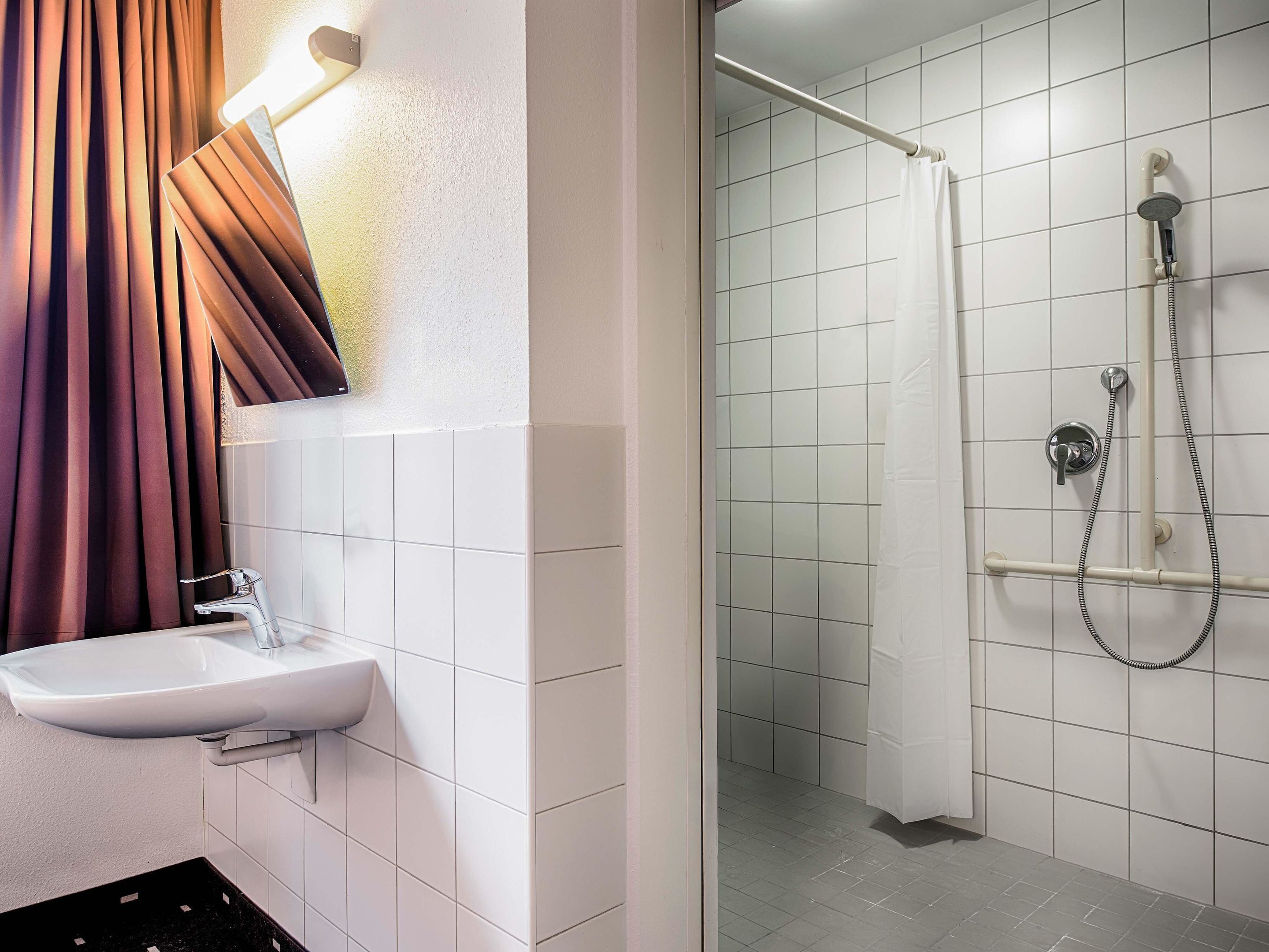 Ein Badezimmer mit einem weißen Waschbecken, einer Dusche mit Duschbrause und einem Duschvorhang.