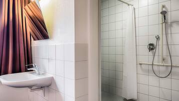 Ein Badezimmer mit einem weißen Waschbecken, einer Dusche mit Duschbrause und einem Duschvorhang.