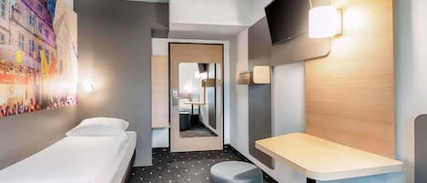 A hotel room with two beds, a desk, a chair, a TV, and a bathroom visible through an open door.