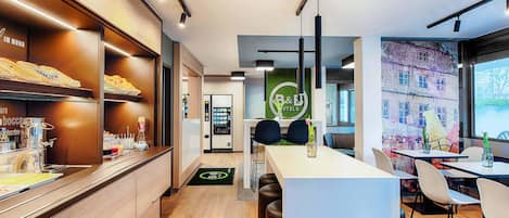 Un moderno vestíbulo de hotel con mostrador de recepción, zona de estar y mesa de buffet.