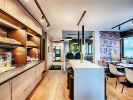 Un moderno vestíbulo de hotel con mostrador de recepción, zona de estar y mesa de buffet.