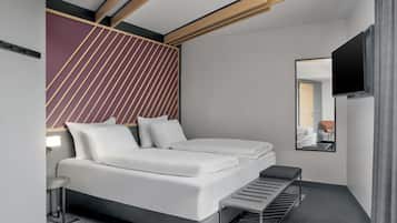 A modern hotel room with a bed, a small table, a bench, a mirror, and a TV.