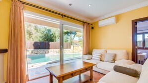 A living room with a sofa, a wooden coffee table, and a sliding glass door leading to a pool area. - House in Alcudia Can Jaume with swimming pool (Alcúdia)