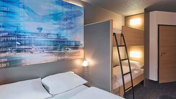 Ein Hotelzimmer mit Bett, einer Leiter, einem an der Wand befestigten Fernseher, der eine Fluganzeige des Flughafens zeigt, und einer Tür.