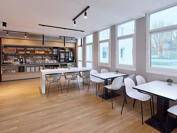 Un café moderne avec un bar, des tables et des chaises blanches.