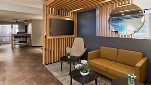 A modern interior with a sofa, a chair, a TV, and a small table with a plant. - B&B Hotel Köln-Airport (Cologne)