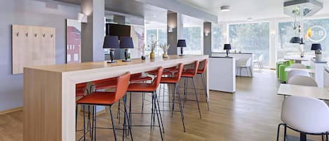 A modern kitchen with a long island counter, bar stools, and pendant lighting.