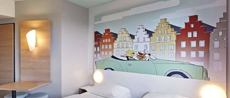 A hotel room with two single beds, a wooden nightstand, a wall-mounted lamp, and a colorful cityscape mural.