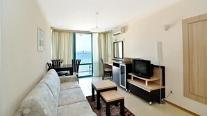 Una sala moderna con un sofá, una mesa de centro, un televisor y un comedor con sillas.
