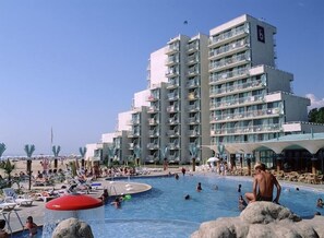 Un hotel con un amplio espacio de piscina, varios balcones y un diseño arquitectónico moderno.
