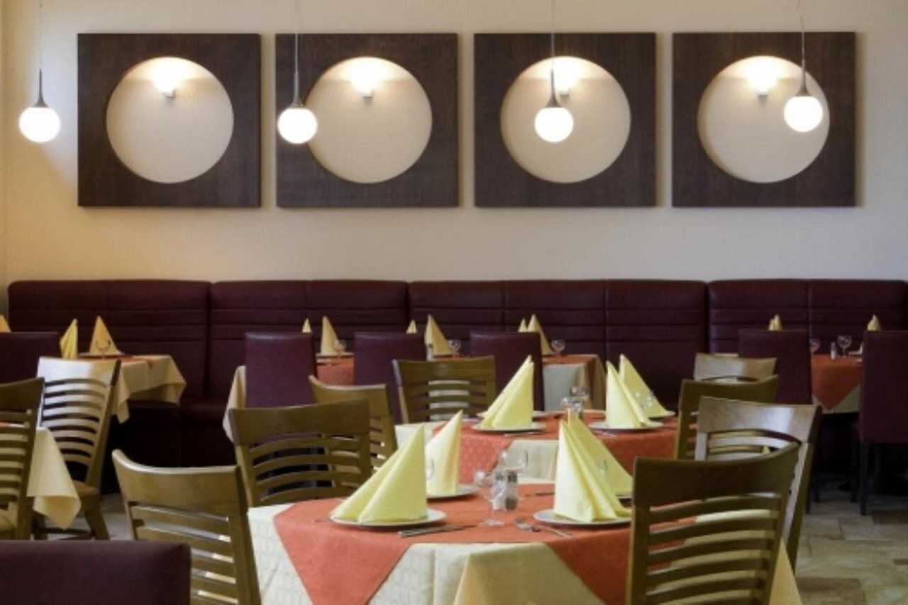 A restaurant with round tables, wooden chairs, and a red upholstered booth.