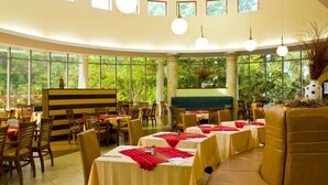 Un restaurante con mesas redondas, sillas e iluminación colgante.