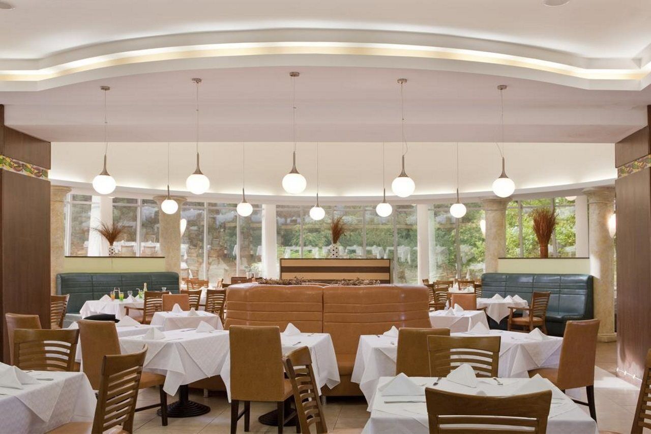 A restaurant with round tables, a central seating area, and large windows.