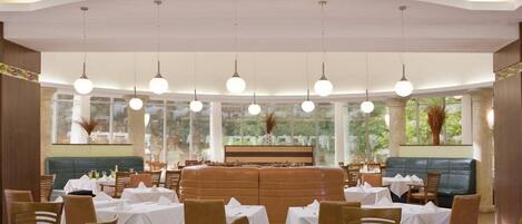 A restaurant with round tables, a central seating area, and large windows.