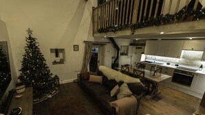 Ein gemütliches Wohnzimmer mit Weihnachtsbaum, einer Couch und einem Esstisch.